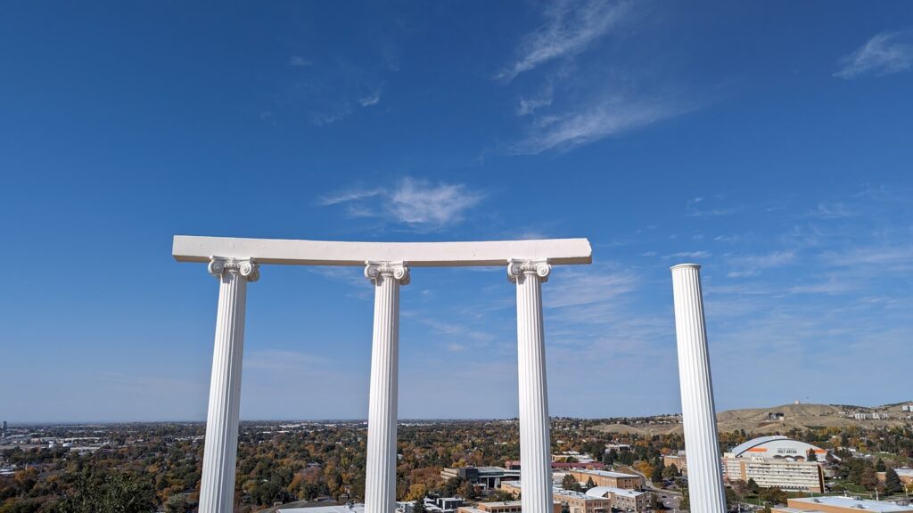 Three white pillars in front of a blue sky