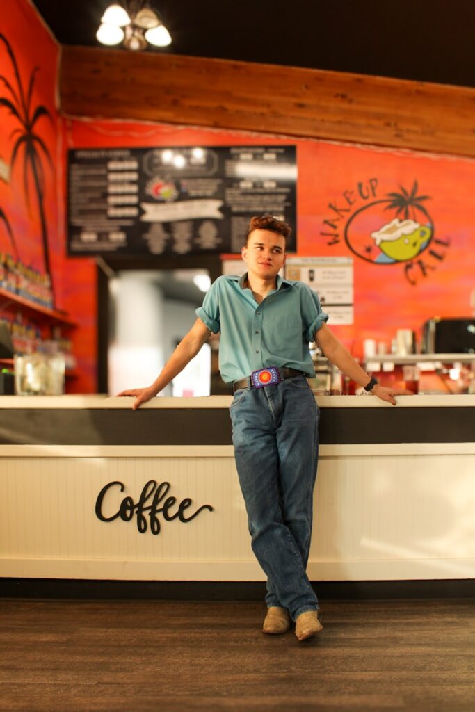 Man leans against the counter in a coffee shop.